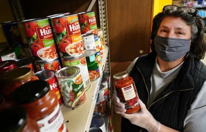Woman holding a jar next to a shelf of canned goods